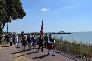 Piper leads procession along Clacton's top promenade with Clacton Pier in the background